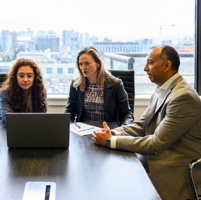 Professionals at table looking at laptop
