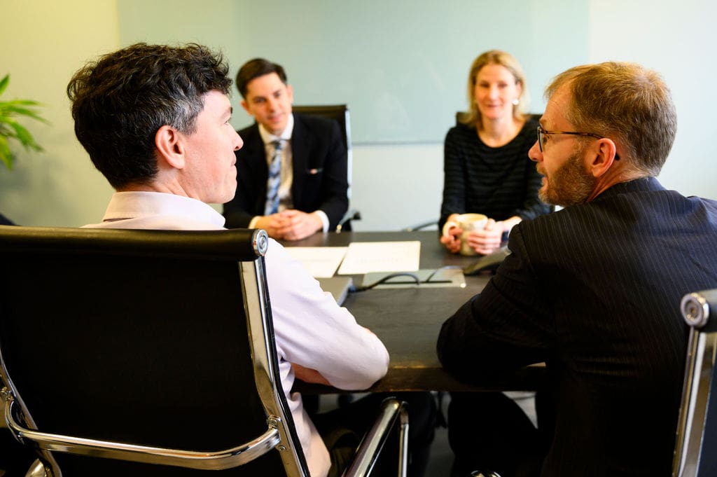 Men seated at table talking with two people seated in background