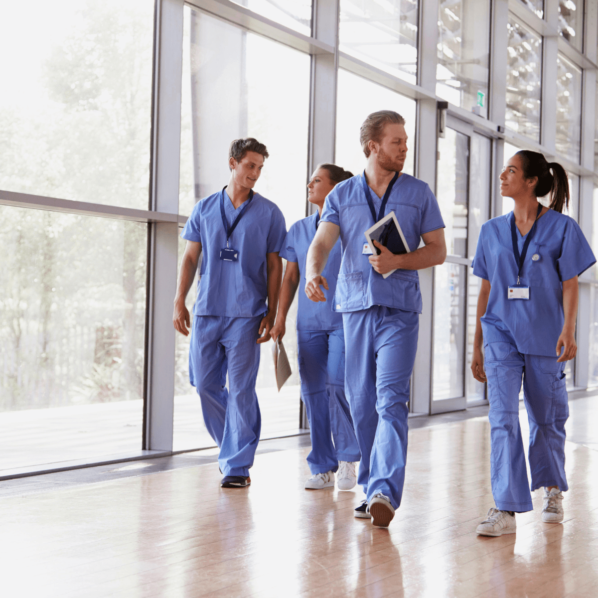 Healthcare workers in blue scrubs walking in hallway