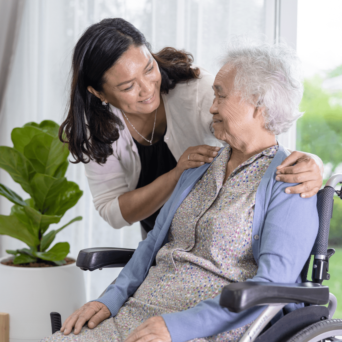 Photo of caregiver comforting old woman in wheelchair